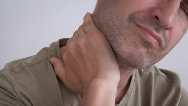 Male feels discomfort neck. A man with sad face expresion feel the discomfort in his neck on the sofa.