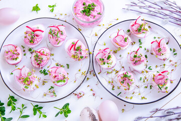 Pink eggs dyed with beetroot juice stuffed with horseradish filling with radish, sprouts and...