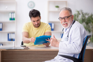 Obraz premium Young male patient visiting old male doctor