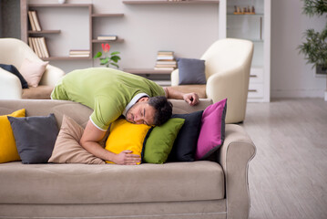 Young man with a lot of pillows sitting on the sofa