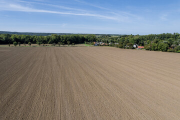 The field is milled, the countryside is trees and houses. Top view of the plantation.