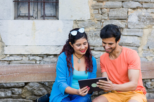 mixed race couple together in Villanueva Asturias using tablet technology outdoors on holyday