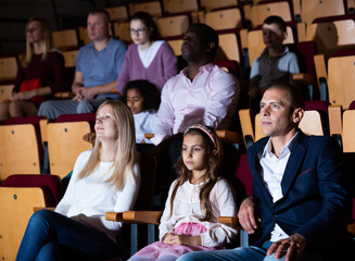 caucasian family sitting at premiere in theatrical hall