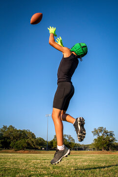 Young preteen 7on7 football player catching ball sunny outside blue sky wearing 7on7 uniform