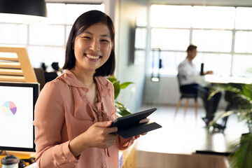 Portrait of happy asian businesswoman using tablet and smiling, working late at office