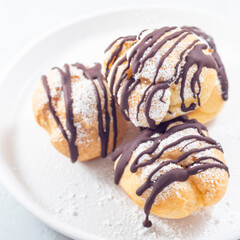 Closeup of profiteroles with whipped cream and chocolate filling, square