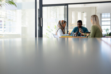 Diverse group of casual business people discussing work at table in modern office