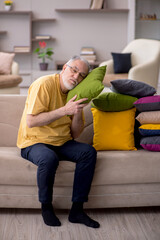 Fototapeta premium Old man with many pillows at home