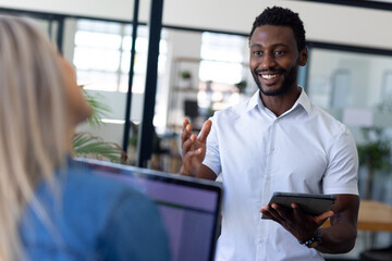 Busy diverse casual business people discussing work and using laptop in modern office