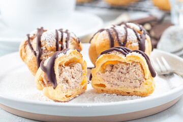 Fototapeta na wymiar Profiteroles with whipped cream and chocolate filling, with melted chocolate, cutted, horizontal