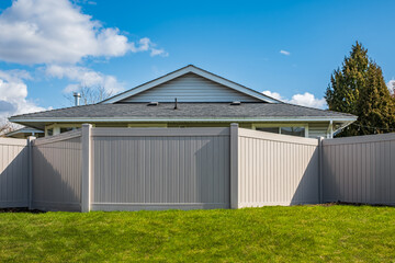 Obraz premium Nice new wooden fence around house. Wooden fence with green lawn. Street photo