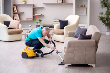 Old male contractor cleaning the house