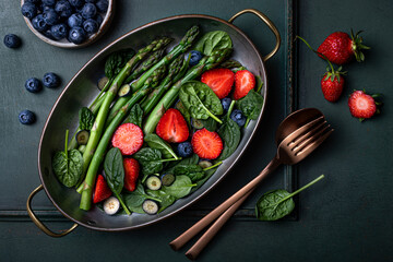 Green asparagus, strawberry, spinach, blueberry salad. Top view