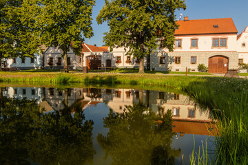 Fototapeta na wymiar Pond and traditional houses of rural baroque style in Holasovice village, Czech Republic