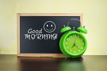 An alarm clock and black chalkboard with a Good Morning message an a smiley face