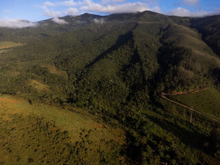 Aerial view of beautiful forest full of nature and pasture fields in Tremembé in Vale da Paraíba in São Paulo. Mountains and hills in sunny day. Lots of green and tropical vegetation. Drone. Sunset