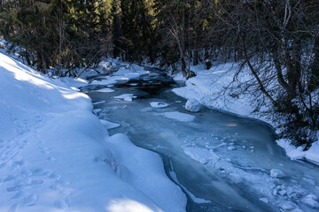 Beautiful frozen river in winter snowy forest