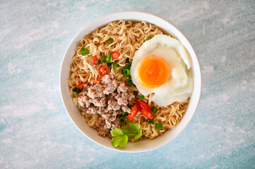 instant noodles cooking tasty eating with bowl - noodle soup, noodles bowl with boiled egg minced pork vegetable spring onion lemon lime lettuce celery and chili on table food