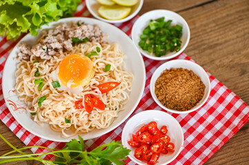 instant noodles cooking tasty eating with bowl - noodle soup, noodles bowl with boiled egg minced pork vegetable spring onion lemon lime lettuce celery and chili on table food