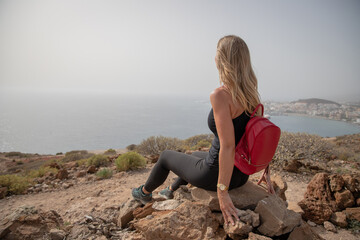 A hiker looks at the sea while relaxing sitting on a rock, love of nature and freedom concept