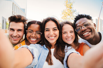 Group of happy multiracial teenagers having fun smiling taking a selfie portrait together on a...
