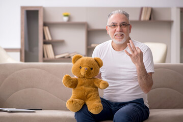 Old man with toy bear at home