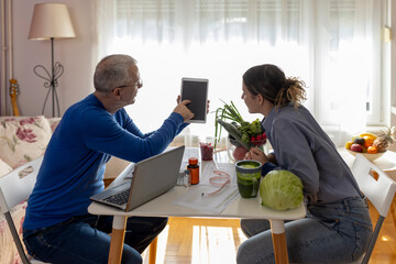 Male nutritionist making weekly meal planner for teen girl patient in office.  Weight loss strategy, calorie control, healthy lifestyle