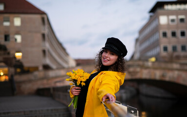 woman with a bouquet of spring daffodils in her hands, walks along the bridge