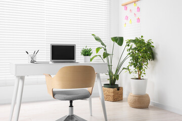 Stylish workplace with desk, chair and potted plants at home