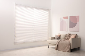 Fototapeta premium Cozy sofa with pillows and blanket in living room, space for text. Interior design