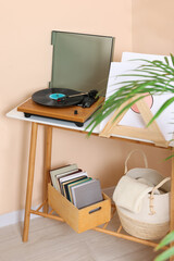 Stylish turntable with vinyl record on console table in cozy room