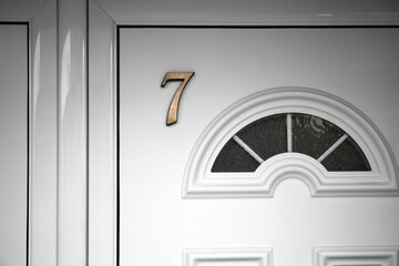 House number seven on white wooden door