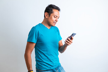 Hombre contento de piel morena de playera azul revisando el celular con fondo blanco