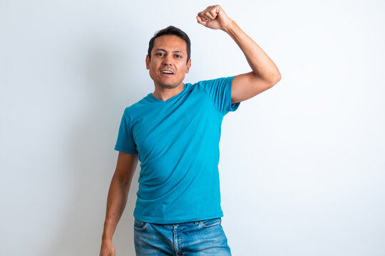 Hombre  Latino De Playera Azul Festejando Levantando El Brazo Con Fondo Blanco