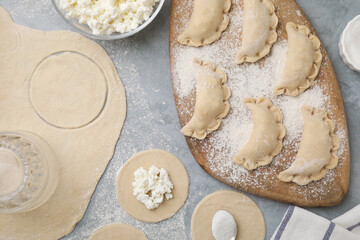 Process of making dumplings (varenyky) with cottage cheese. Raw dough and ingredients on grey table, flat lay