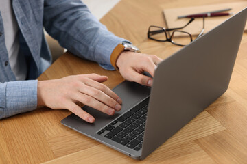 Man working on laptop at wooden desk, closeup