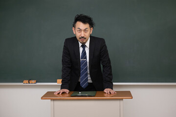 教壇の黒板の前に立つ男性教師 - obrazy, fototapety, plakaty