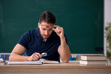 Young male teacher sitting in the classroom