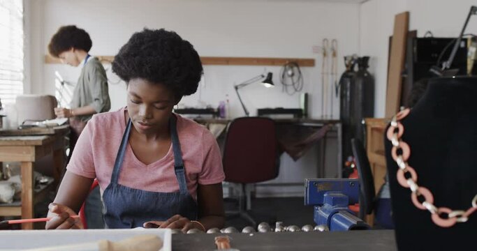 Busy african american female worker drawing design of jewellery in jewellery studio in slow motion