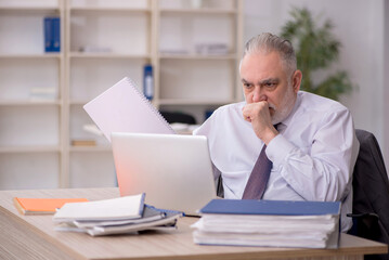 Naklejka premium Old male employee working in the office