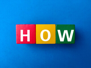 Colored wooden block with the word HOW on blue background.