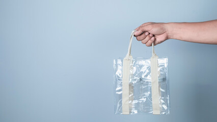 Fototapeta na wymiar Hand holding plastic bag on blue background, Recycling concept.