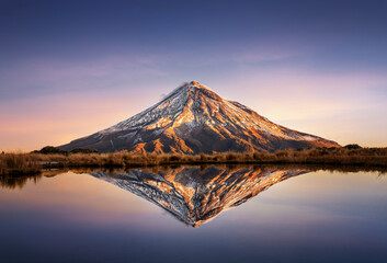Mount Egmont or also called Taranaki with a mirror effect in a little lake in Egmont National Park during sunset, New Zealand 