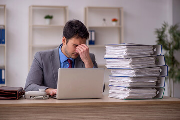 Young male employee and too much work in the office