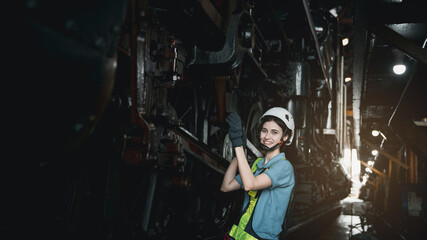 Fototapeta na wymiar Engineer are working in the factory. Worker helping to repair and inspect the machine's readiness. Mechanical technicians are maintaining the engine in the train garage that is malfunctioning.