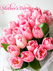 Inscription mothers day with bunch of light gentle pink tulip, bouquet flowers