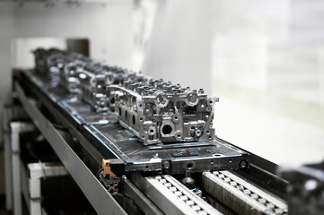 Car engine cylinder heads in housings on conveyor in shop