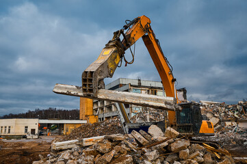 Obraz premium Excavator with hydraulic press breaks concrete leftovers