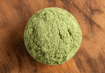 A Bowl of Green Kale Powder on a Wood Counter Top