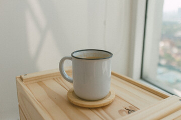 Coffee cup on a wooden crate in a warm morning.